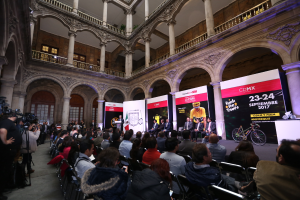 Eine Gruppe von Menschen, die an einem Tisch mit einem Podium und einem Mikrofon vor einer Menge, Kameras und Bannern sitzen, was auf eine Pressekonferenz für das CDMX 2017-Event hinweist.