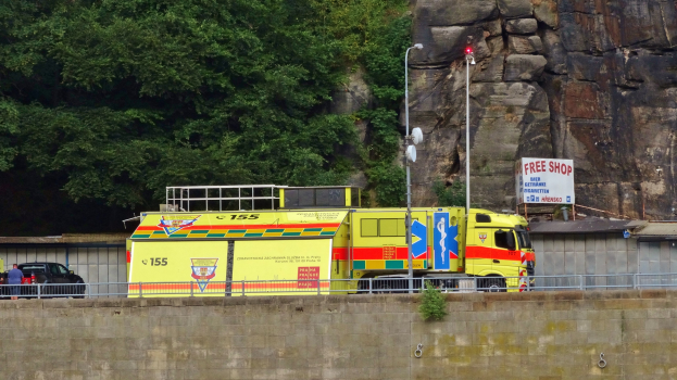 Rettungswagen neben einer Straße neben einer Klippe geparkt, mit Bäumen und einem Auto im Hintergrund.
