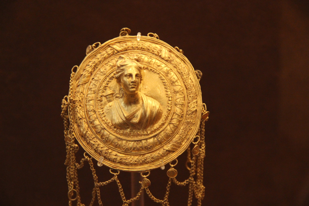 Goldene Medaille mit einer Frauengestalt auf dunklem Hintergrund, mit feinen Details und einem majestätischen Aussehen.