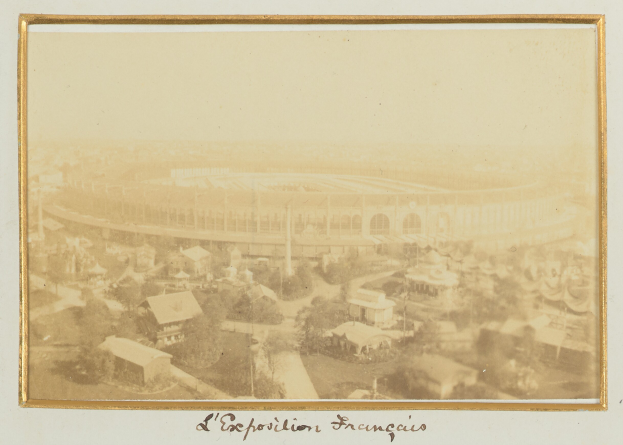 Altes Schwarz-Weiß-Foto eines Stadions in städtischer Umgebung mit umliegenden Gebäuden, Bäumen und Strommasten, mit Text unten.