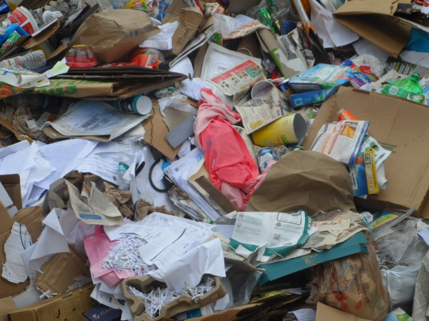Ein unordentliches Durcheinander aus Kartonschachteln mit verschiedenen Gegenständen wie Papieren, Flaschen und Abdeckungen.