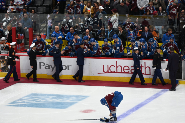 Ein Eishockeyspieler auf dem Eis umgeben von Fans und Teammitgliedern während eines Spiels zwischen Colorado Avalanche und San Jose Sharks am 24. März 2015.