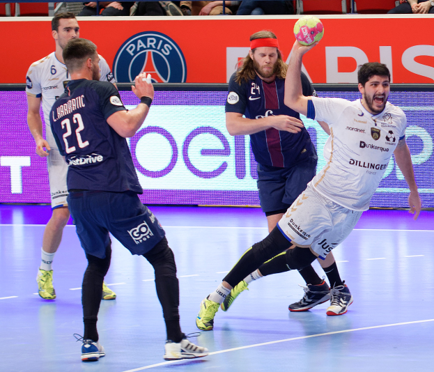 Männer beim Handballspielen auf einem Feld mit einem Ball im Spiel, Zuschauer im Hintergrund und ein Banner mit der Aufschrift "Futsal-Weltmeisterschaft 2019 - Paris Saint-Germain vs. Marseille."