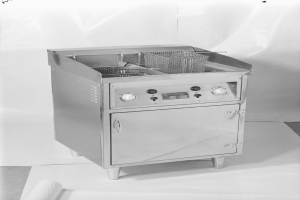 Ein Schwarz-Weiß-Foto eines Gasfritiers mit einem Korb darauf, das auf einem Tisch steht.