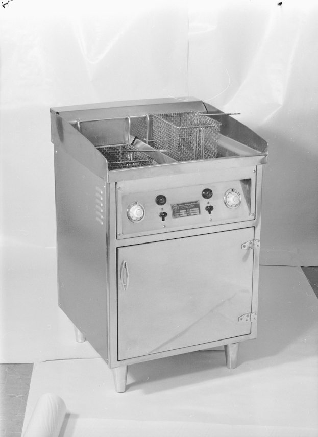 Ein Schwarz-Weiß-Foto eines Gasfritiers mit einem Korb darauf, das auf einem Tisch steht.