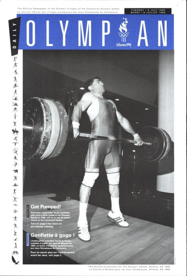 Schwarzes und weißes Foto eines Olympiamagazin-Covers mit einem Mann in einem Gewichtheber-Outfit, der eine Hantel mit entschlossener Miene hochhebt, mit dem Magazintitel oben drauf.