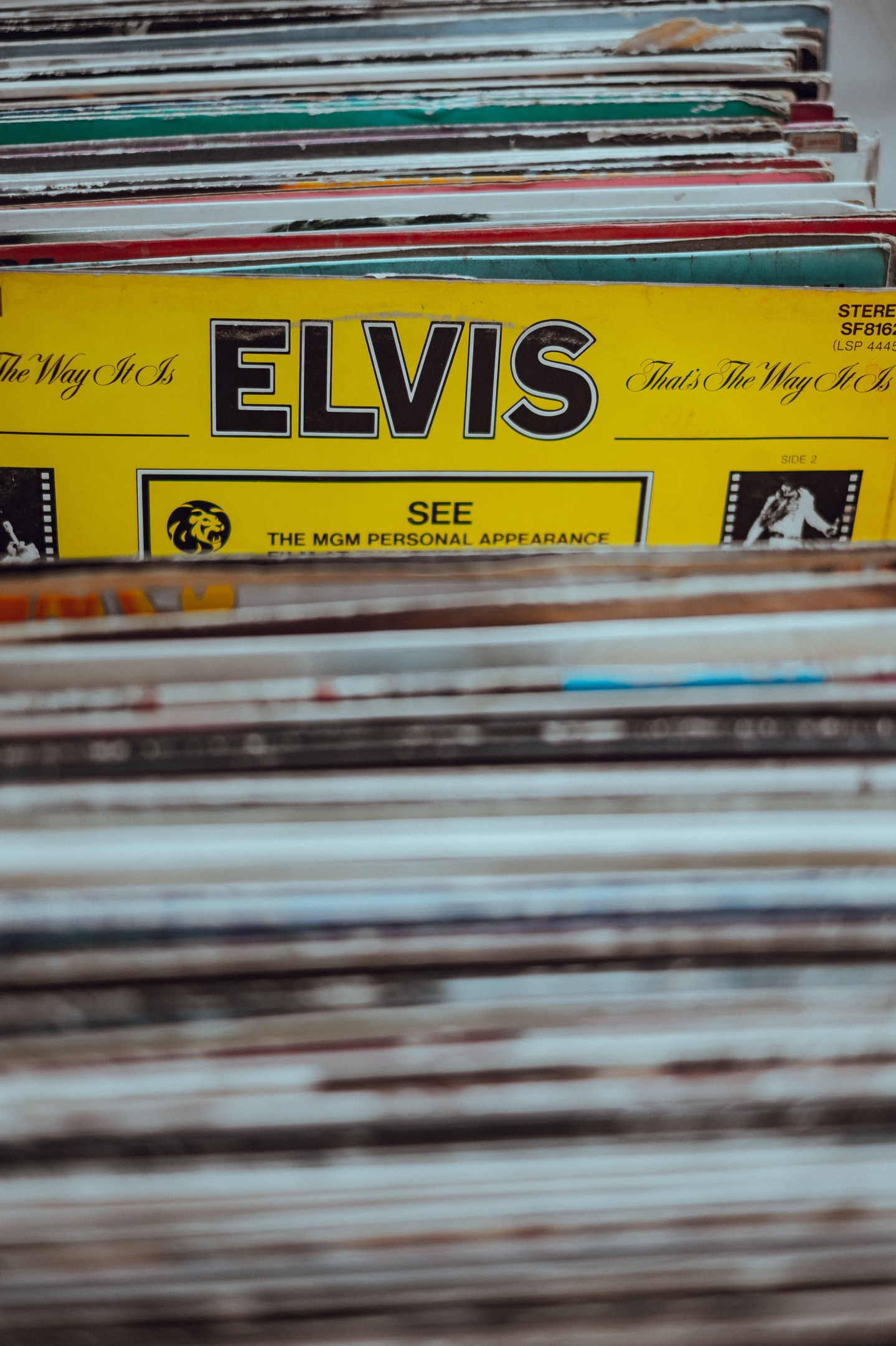 Ein ordentlich gestapelter Stapel Elvis-Presley-Platten mit sichtbaren Titeln auf einem leicht unscharfen Hintergrund.