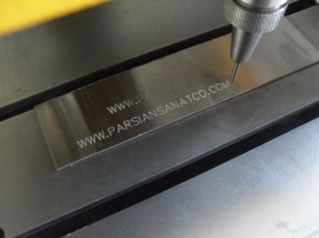 CNC-Fräsmaschine schneidet ein Metallteil mit eingravierter Text.