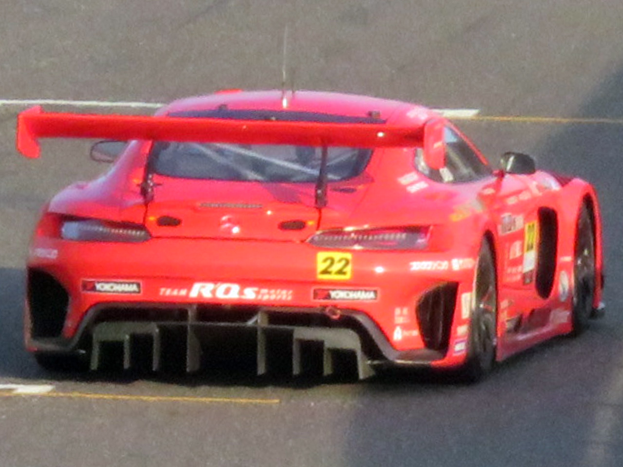Roter Porsche 911 GTS Rennauto auf einer Rennstrecke mit aerodynamischem Design, großer Heckflosse, breiten schwarzen Rädern und niedrigem Profil.