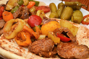 Ein Teller mit Tomaten, Chilischoten und Hühnerstücken.