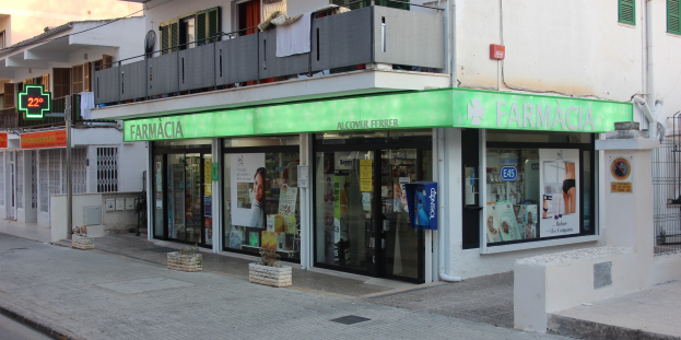 Apotheke an einer Straßenecke mit umliegenden Gebäuden, Fahrzeugen und einem klaren Himmel.