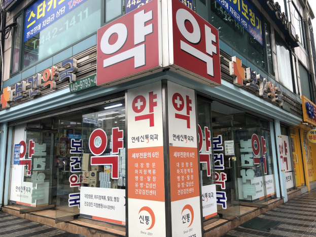 Außenansicht einer modernen Glasfassade einer Apotheke in Seoul, Südkorea, mit Text, der darauf hinweist, dass es sich um die erste Apotheke in der Stadt handelt.