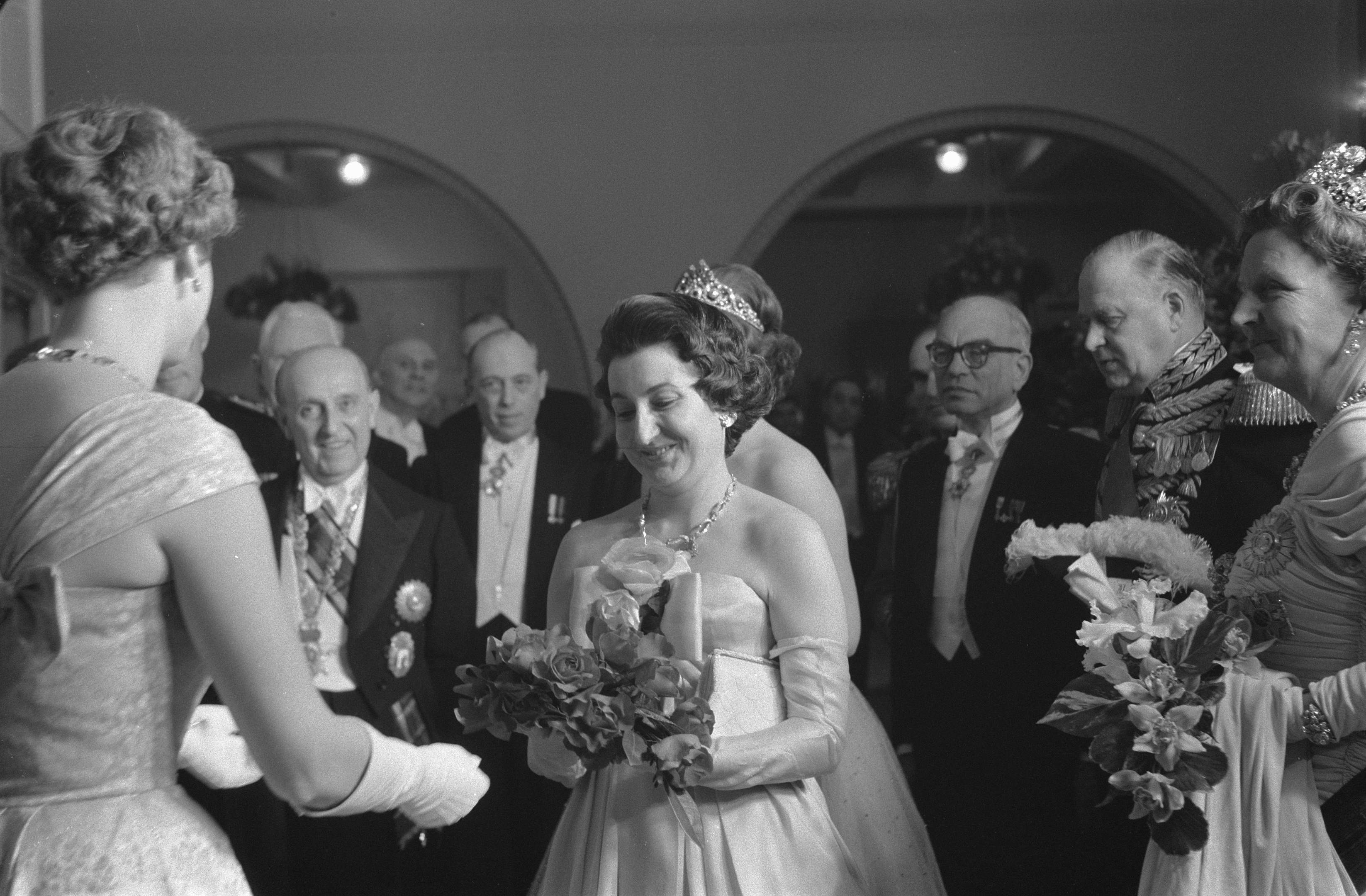 Schwarzes und weißes Foto von Queen Elizabeth II. und Prinz Philip, Duke of Edinburgh, an ihrem Hochzeitstag mit Kronen und Blumensträußen, umgeben von einer Gruppe von Menschen.