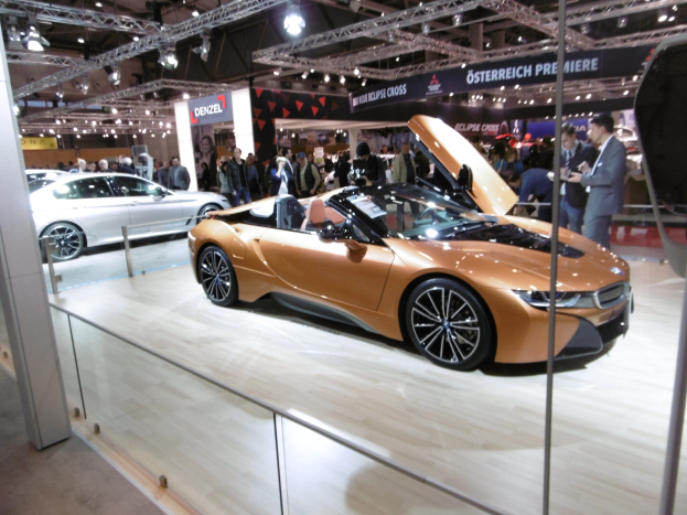 Ein schickes schwarzes BMW i8 Cabrio mit Chromakzenten auf der Frankfurter Motor Show umgeben von formell gekleideten Gästen.