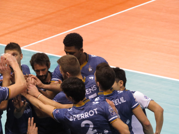 Eine Gruppe von Männern in blauen "Ligue 1" T-Shirts feiert auf einem Volleyballfeld.