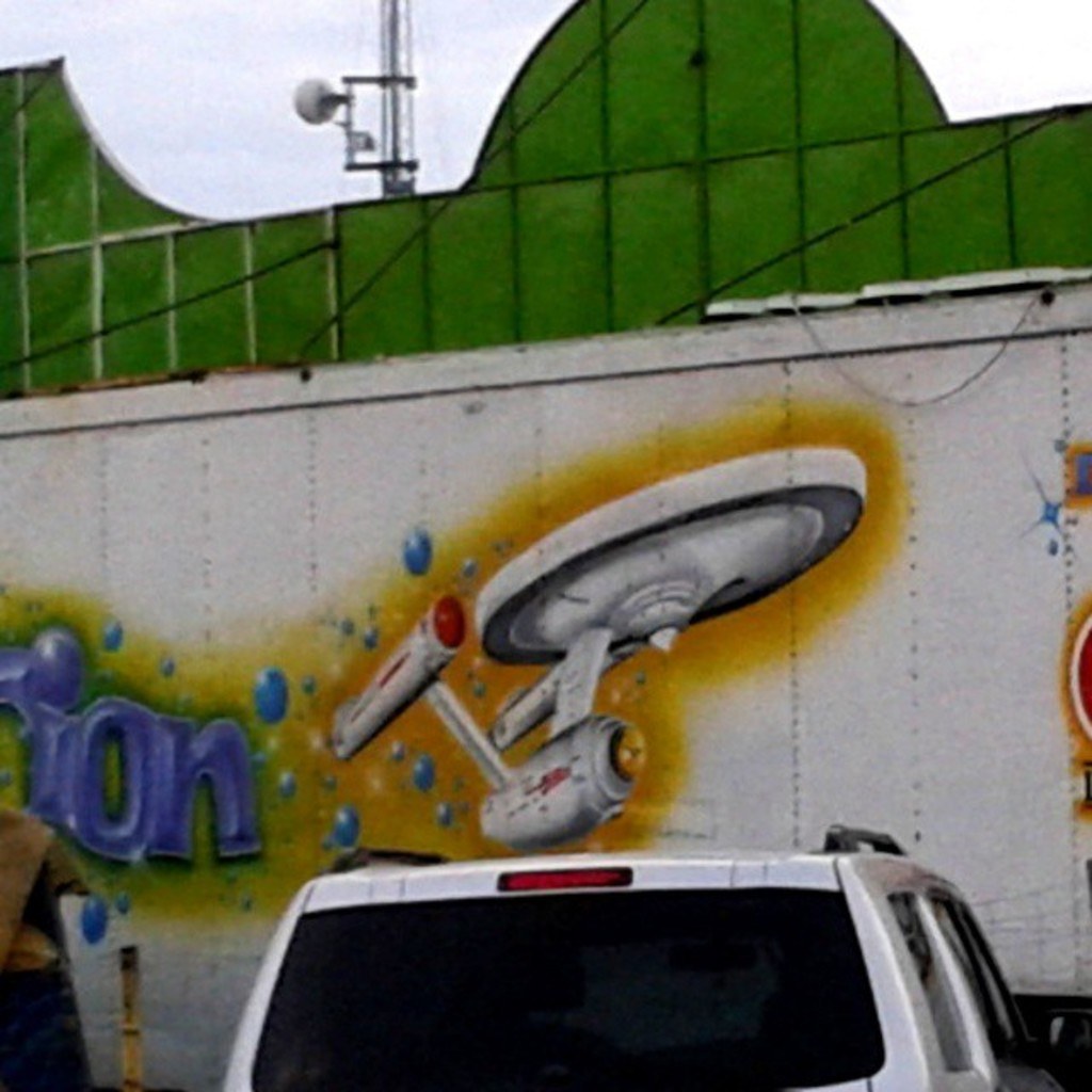 Ein Auto, das an einer Wand mit einem Bild geparkt ist.