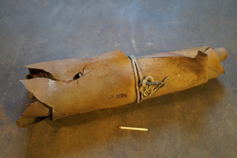 Papiertüte, die wie eine Granate aussieht, mit einer Zigarette daneben auf einem Tisch, mit einem Seil zusammengebunden.