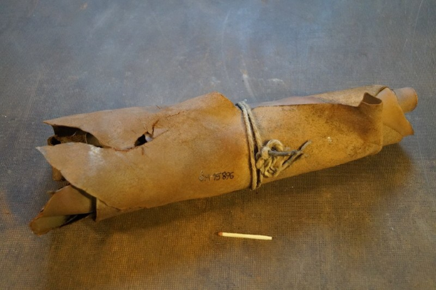 Papiertüte, die wie eine Granate aussieht, mit einer Zigarette daneben auf einem Tisch, mit einem Seil zusammengebunden.