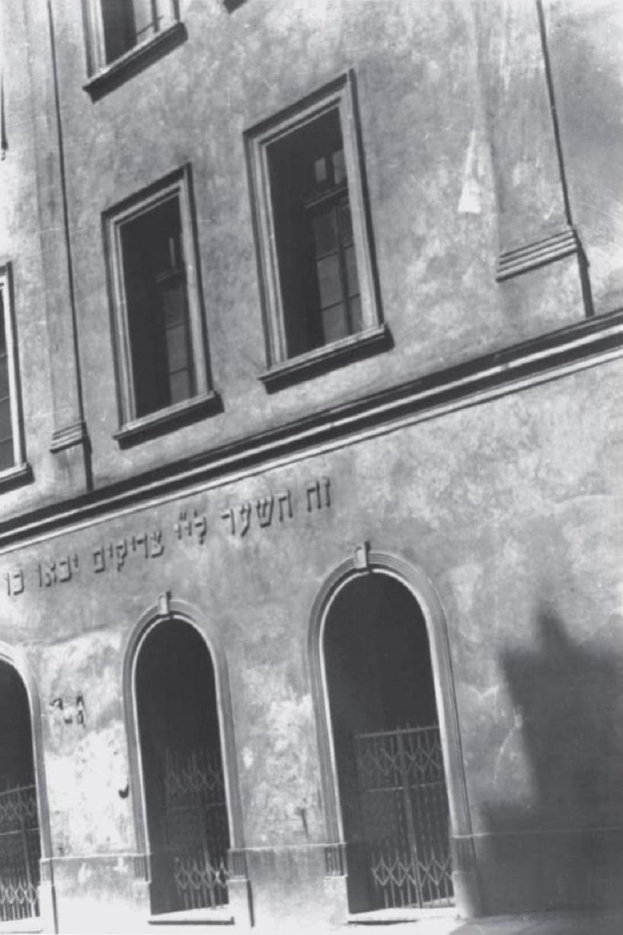 Ein Schwarz-Weiß-Foto eines Gebäudes mit Fenstern, Türen und einem Metallzaun, das als Synagoge der jüdischen Gemeinde in Jerusalem vermutet wird.