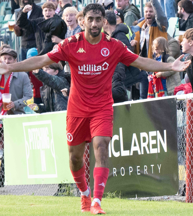 Ein Fußballspieler in roter Uniform rennt auf einem Feld mit ausgestreckten Armen, umgeben von Zuschauern, mit einem Banner "Middlesbrough FC v Swansea City - Sky Bet Championship" im Vordergrund.