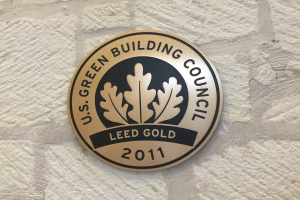 Das Logo des U.S. Green Building Council auf einem Gebäude, das einen Schild mit grünem Hintergrund und weißer Umrandung zeigt, die Wörter 'Green Building Council' in fetter schwarzer Schrift und einen umgebenden Lorbeerkranz.